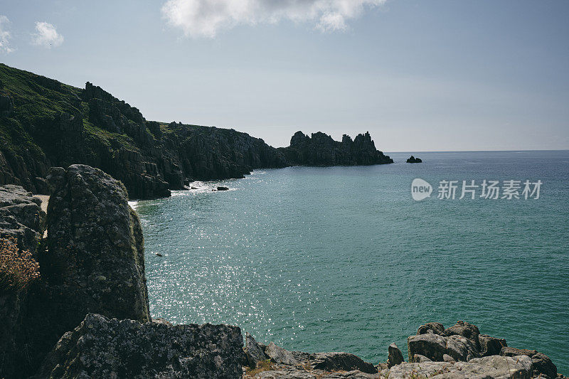 六月初的早晨，在康沃尔郡的佩顿·温德海滩，涨潮时，远处的洛根岩石。