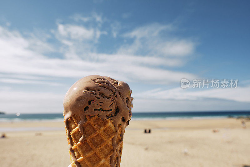 康沃尔纽基，阳光明媚的海滩上，蓝天和大海散焦，美味的融化巧克力甜筒。