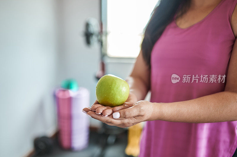 一个女人在家庭健身房拿着青苹果的特写镜头