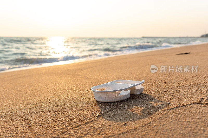 由聚丙烯制成的一次性食品托盘包装留在海滩上，被环境和海水降解，造成微塑料和环境问题