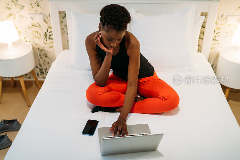 漂亮的黑人女人无聊地在卧室里摆弄笔记本电脑