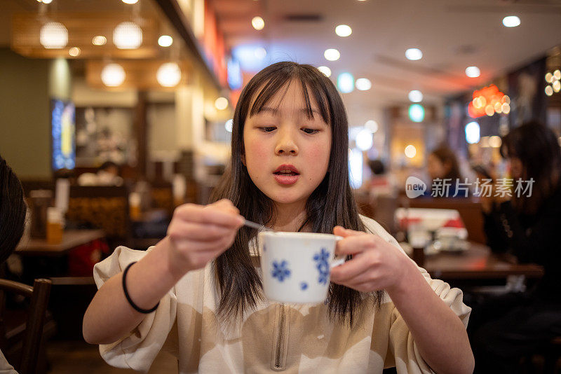 一个十几岁的女孩在餐厅吃完午饭后喝着一杯茶