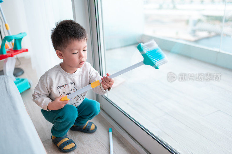 两岁半的小男孩一边愉快地打扫房子，一边玩家务活动