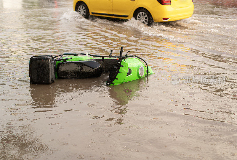 轻便摩托车在雨中撞毁在被水淹没的街道上