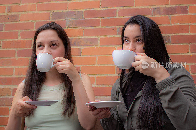 两个年轻女人在沙发上聊天，喝着咖啡