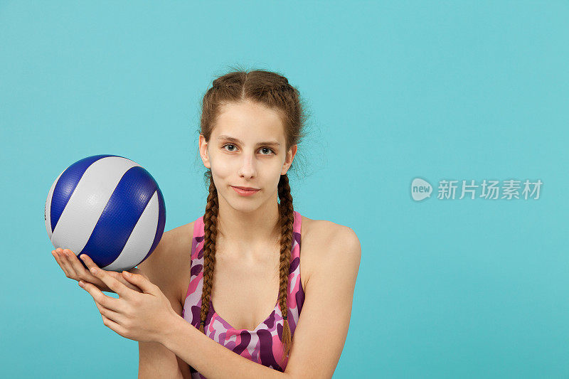 特写肖像的少女14岁在工作室的蓝色背景与排球
