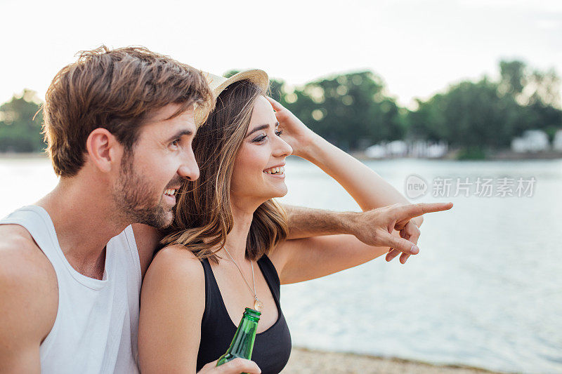 一个拿着啤酒的男人抱着一个女人望着远方