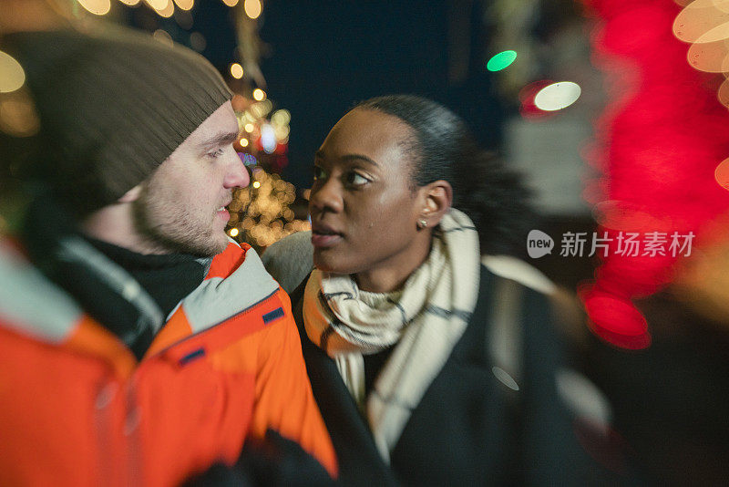 跨种族的相爱的夫妇，美丽的黑人年轻女子和英俊的年轻男子，在纽约布鲁克林观看圣诞彩灯和在寒冷的冬日里玩耍。