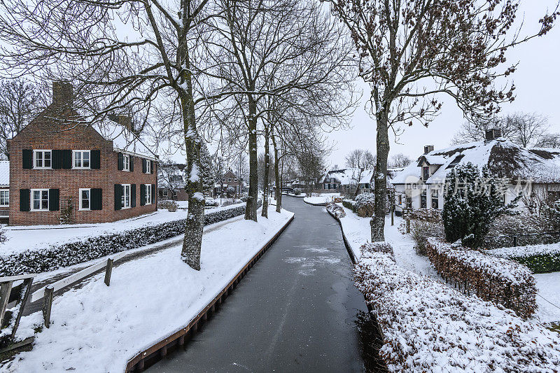 在一个寒冷但美丽而平静的冬天，Giethoorn村的运河和积雪