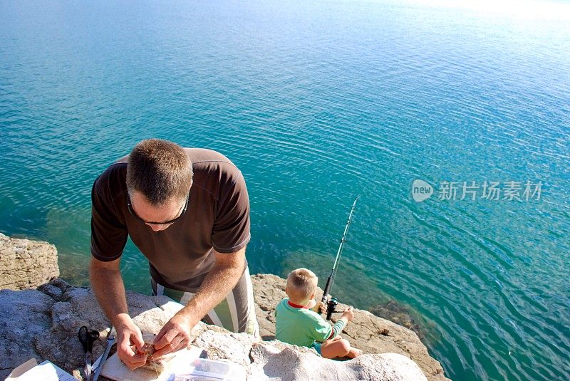 一个父亲和他的孩子在海岸岩石上钓鱼