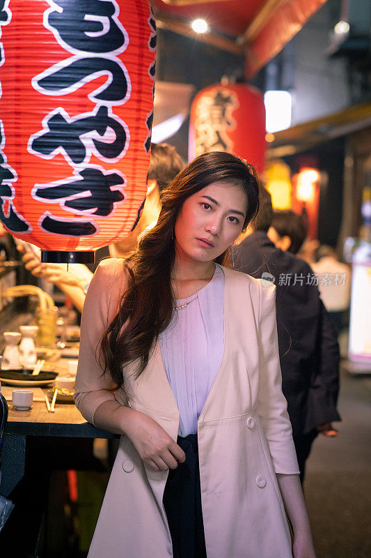 在户外日本居酒屋酒吧的年轻亚洲女人的肖像