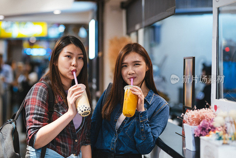 台北西门鼎街，两个快乐的女孩在享受珍珠奶茶