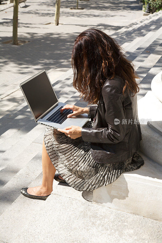 坐着女商人打字，敲击便携式笔记本电脑空白屏幕