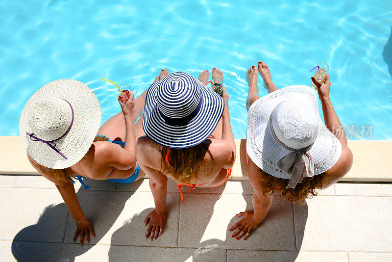 年轻女子太阳帽坐在池边度假泳池避暑