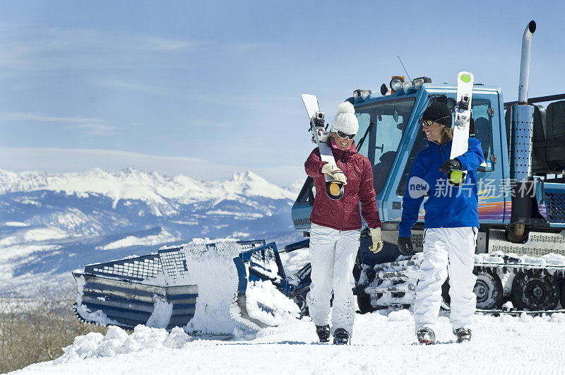 雪地上的滑雪者们以高山为背景，边走边聊
