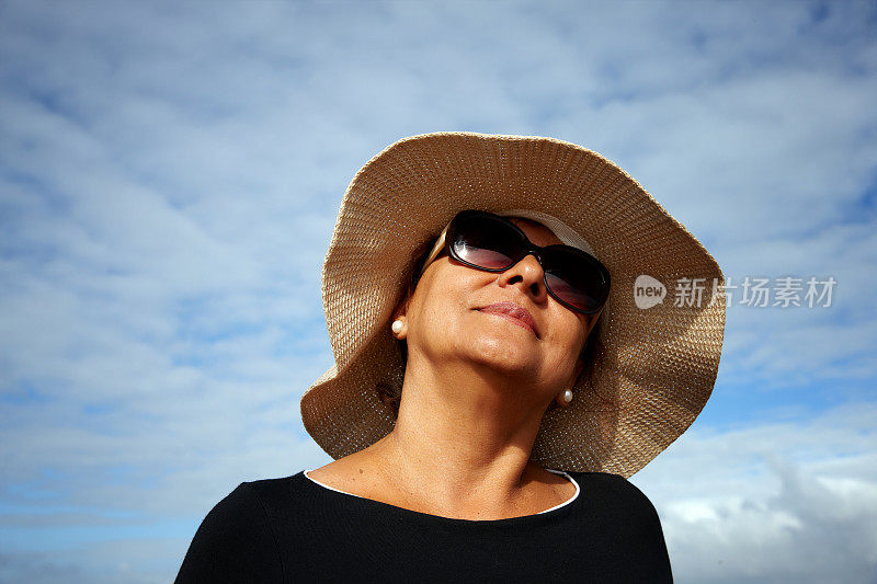 成熟微笑的西班牙妇女太阳镜和太阳帽