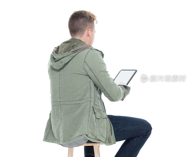 男人坐在凳子上使用平板电脑的后视图