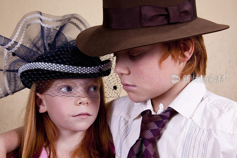男孩和女孩在大人的帽子里玩耍打扮。