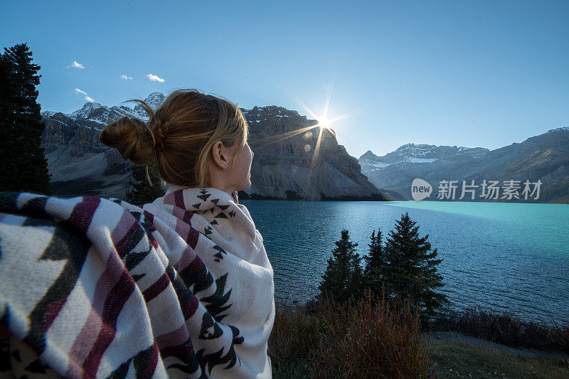 日落时分，一位年轻女子在湖边伸开双臂