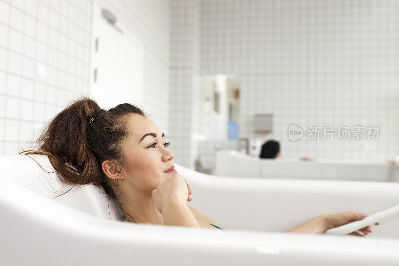 年轻的亚洲女人放松在水按摩浴缸