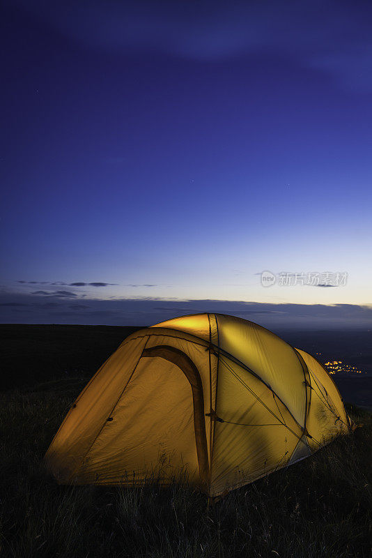 黄昏时分，橘黄色的圆顶帐篷被照亮在山脊上