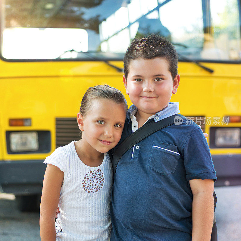 一个孩子和他的女朋友在一辆校车前面