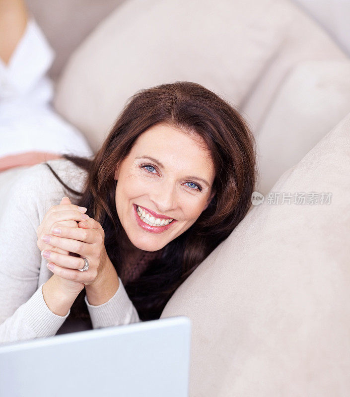 一个很成熟的女人躺在沙发上前面放着笔记本电脑