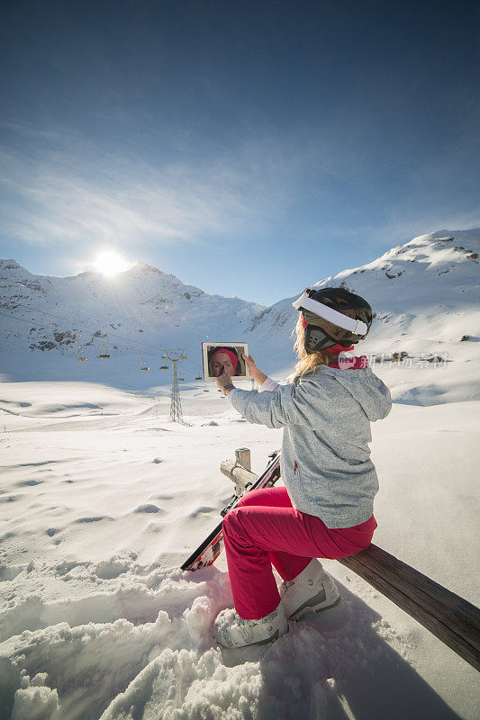 一名女子在滑雪场用平板电脑拍照