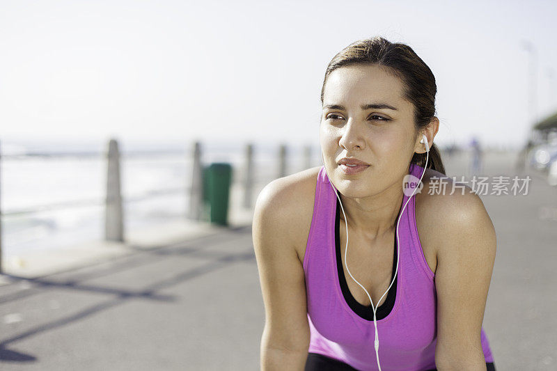 美丽的女人跑步后在海滩边休息