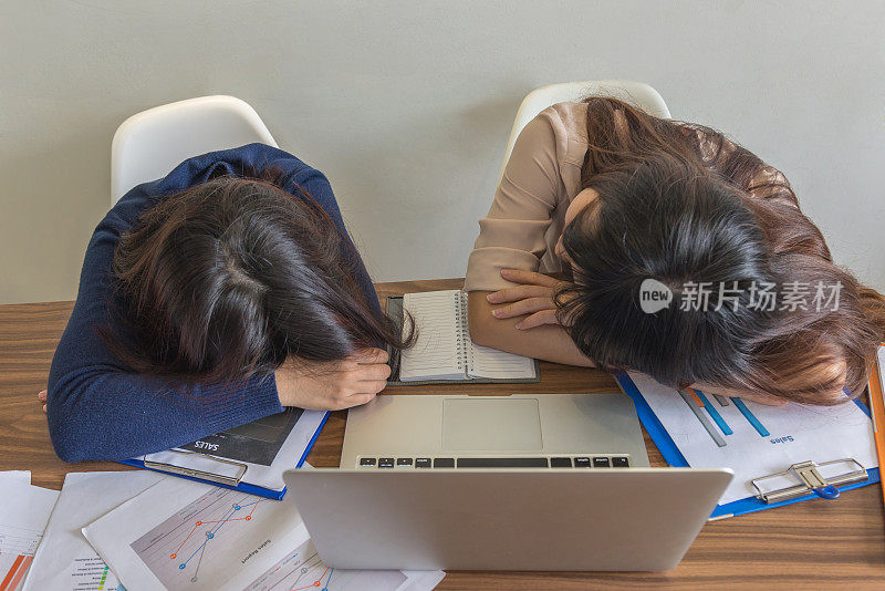 昏昏欲睡的亚洲女孩在办公桌前休息一会儿