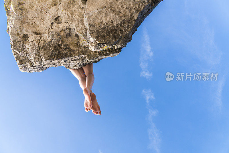 十几岁的女孩坐在悬崖边上，俯视山下。