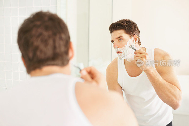 男人在镜子前刮胡子