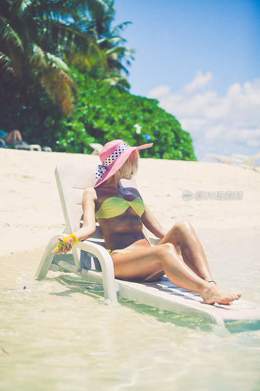 在马尔代夫的浅水里晒日光浴，坐在安乐椅上休息