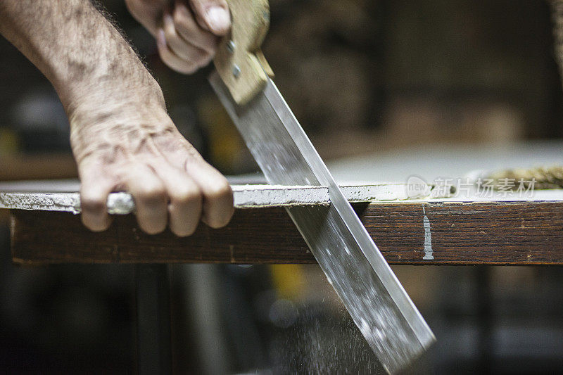 木匠用锯子锯一块石膏板