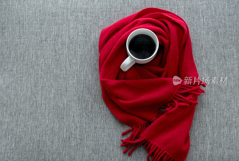 白色咖啡杯和红色羊毛围巾放在沙发上