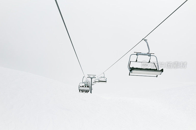 滑雪者在冬季滑雪场缆车索道上滑雪，云雾缭绕