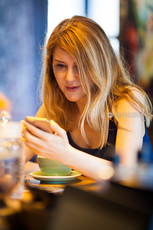 一名女子在咖啡馆使用智能手机