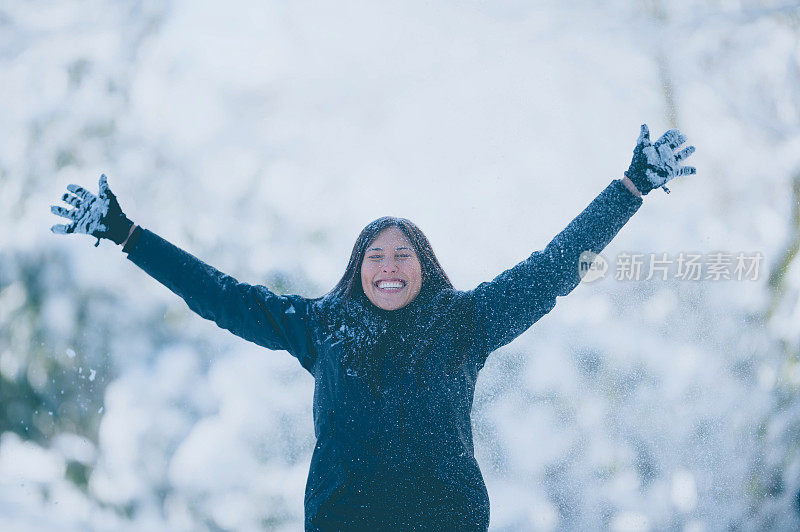 美丽的女人高举着她的双臂，在森林里，白雪像瀑布一样环绕着她