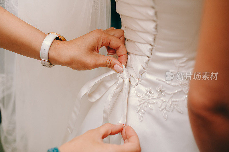 伴娘帮新娘穿上婚纱