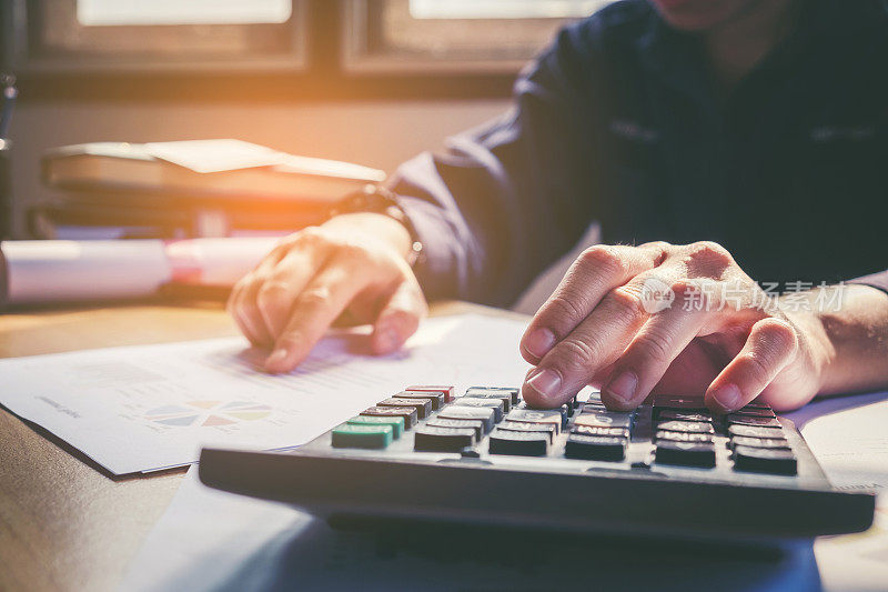 商人的手与计算器在办公室和财务数据分析计算在木桌上