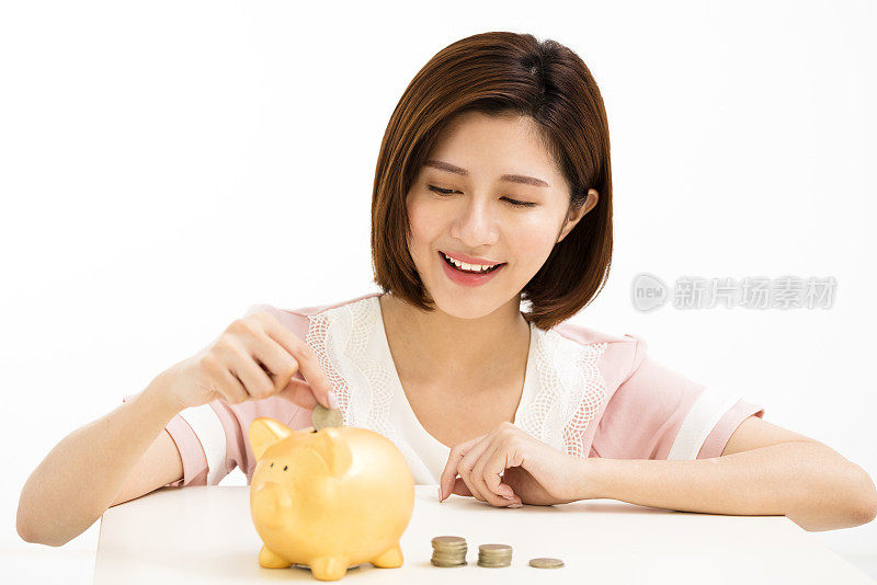 微笑的年轻女子把硬币放进小猪储蓄罐