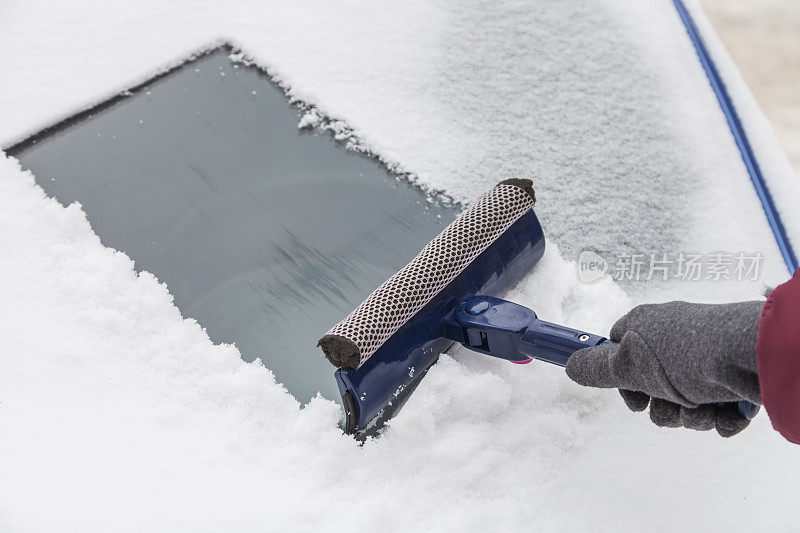 用刮刀清理挡风玻璃上的积雪