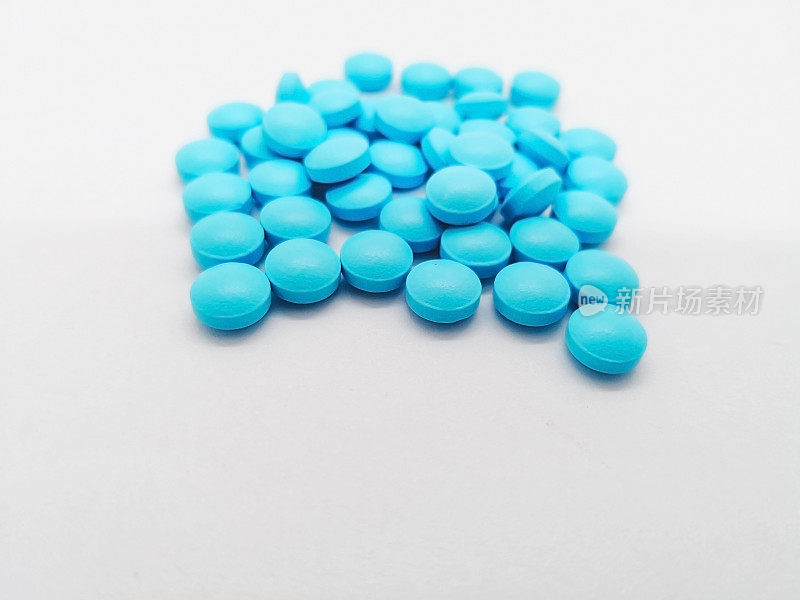 医疗保健理念。许多圆形的蓝色药丸5毫克的seratioptidase。孤立于白色背景，对疼痛和炎症有益。选择性聚焦和复制空间。