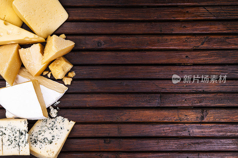 各种各样的奶酪放在质朴的木桌上，俯视图