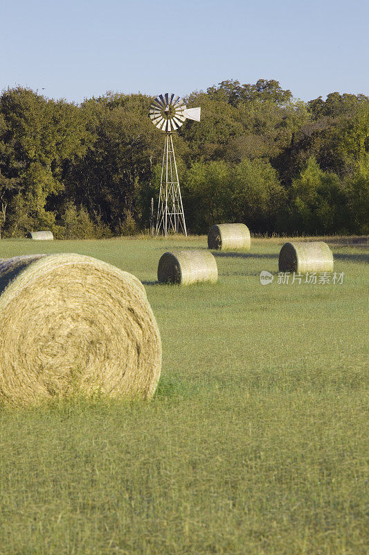 干草在田间滚动，风车在背景