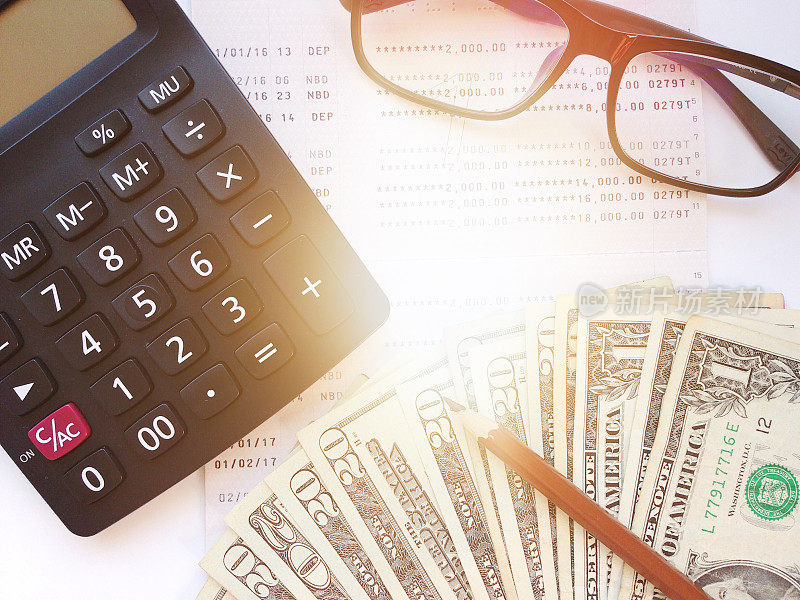 铅笔，计算器，钱，眼镜和储蓄存折或财务报表的白色背景