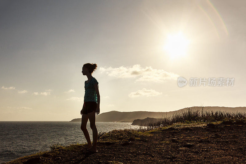 年轻的女孩在悬崖顶上看着大海