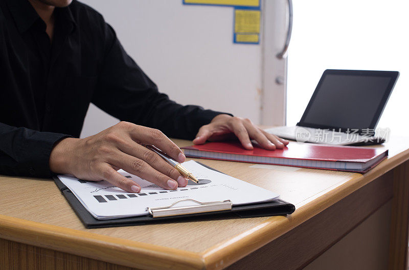 商务人员在办公桌旁用数字平板电脑处理商务文件，后台绘制财务图表