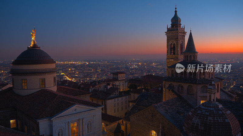 意大利贝加莫。旧的城市。鸟瞰图圣玛丽亚马乔里大教堂和教堂Colleoni在日落。背景是波河平原