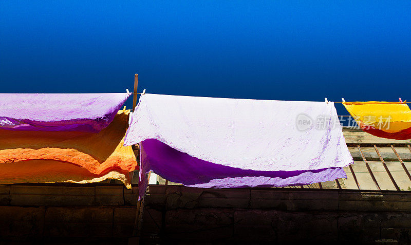 充满活力的紫色和橙色床单在洗衣线上